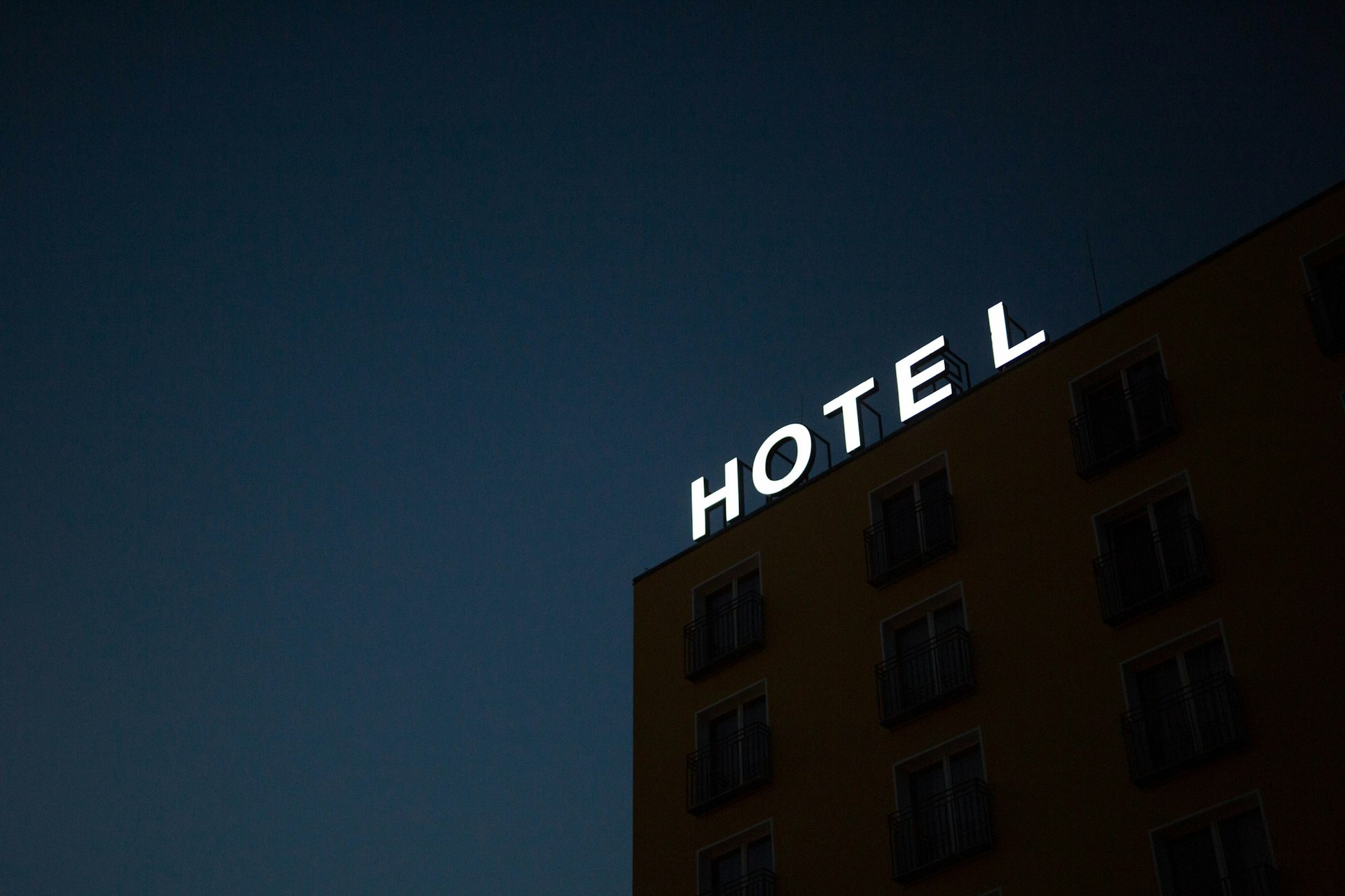 Leuchtschrift „Hotel“ an einer Hausfassade bei Nacht